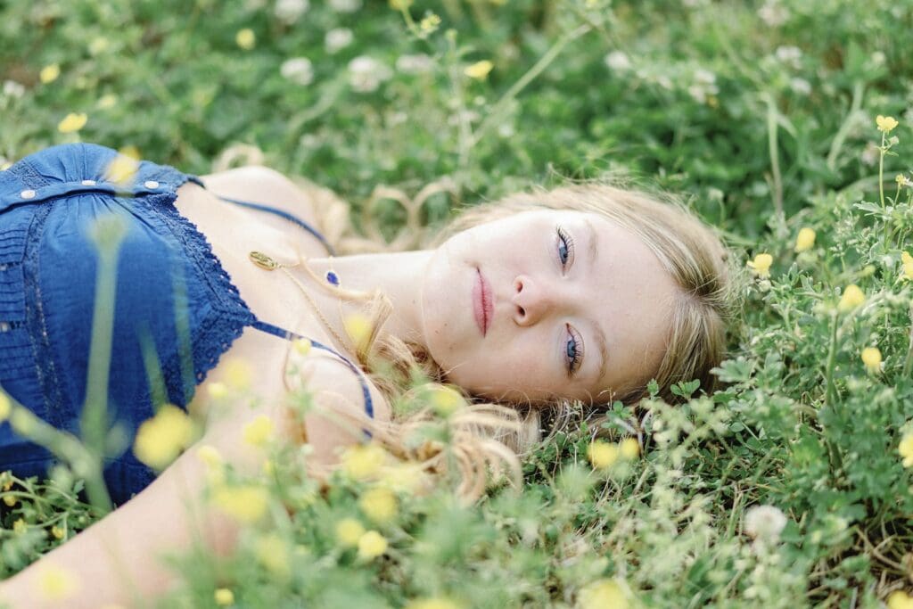 High School Senior Portrait Girl laying in field of little yellow flowers